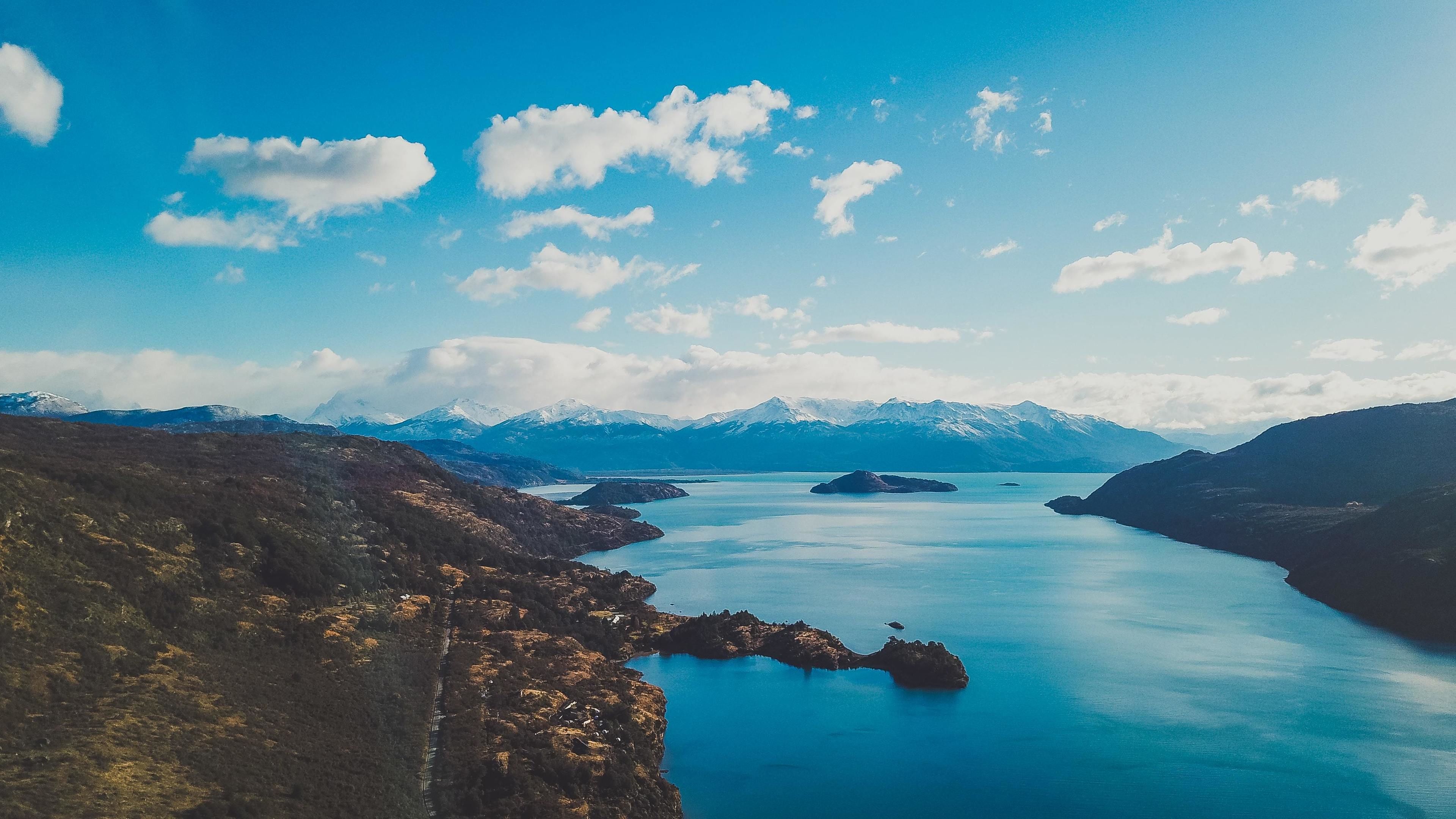 Een panoramisch uitzicht op een kustlandschap, met bergen op de achtergrond en een rustig wateroppervlak op de voorgrond.