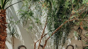 A patio with terracotta tiles, wooden chairs, and potted plants. - The Boathouse Hotel (Santorini)