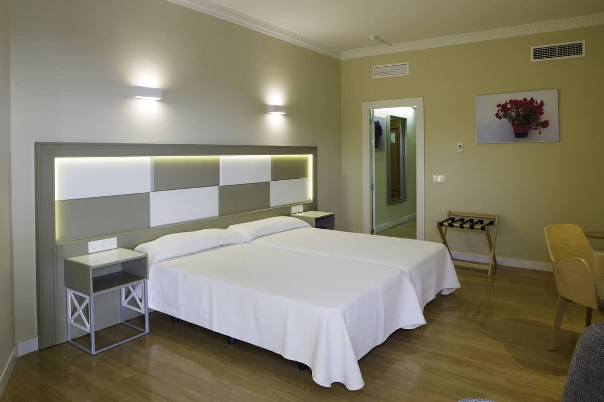 A hotel room with a large bed, bedside tables, a chair, and a mirror.