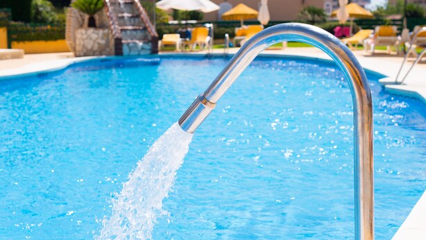 A swimming pool with a water fountain feature, surrounded by lounge chairs and umbrellas. - Hotel Monarque Torreblanca (Fuengirola)