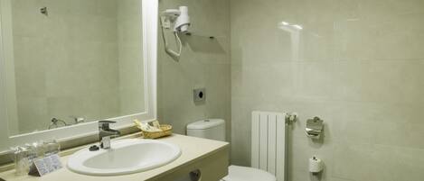 Een badkamer met een wastafel, spiegel, toilet en douchetoilet.