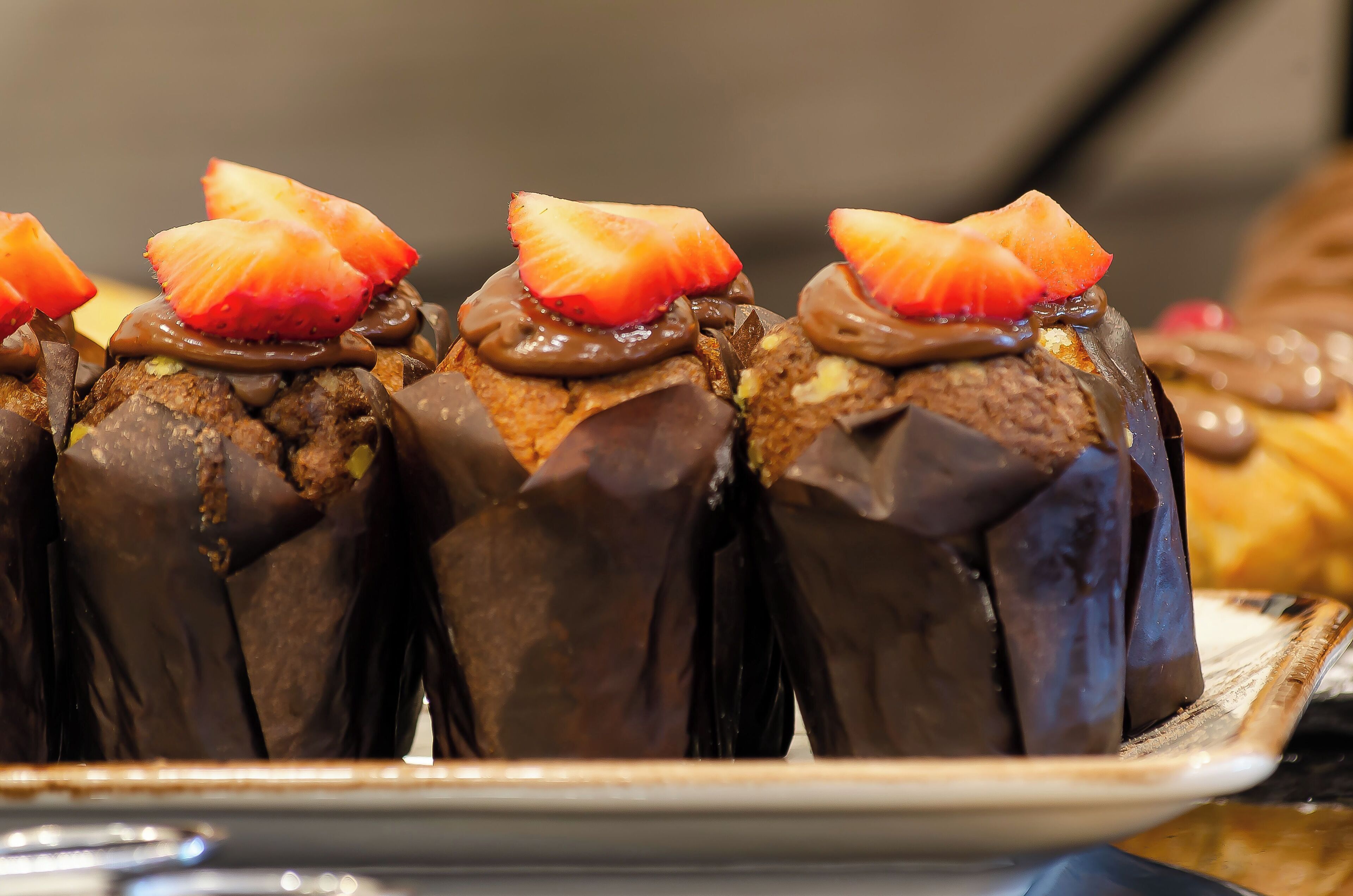 A dessert tray with chocolate-covered pastries topped with strawberries.