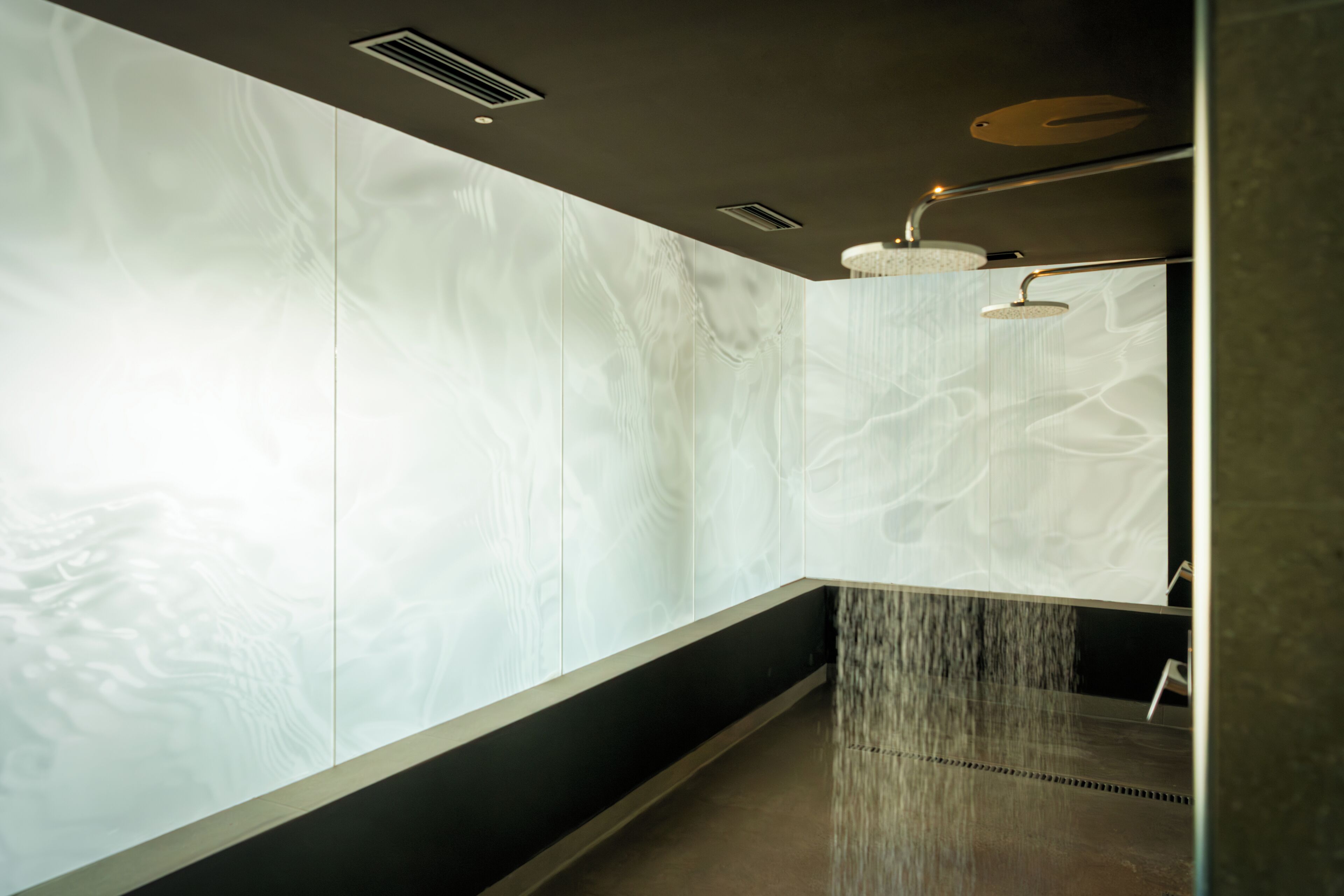 A modern bathroom with a large mirror, a wall-mounted sink, and a shower with a curved design.
