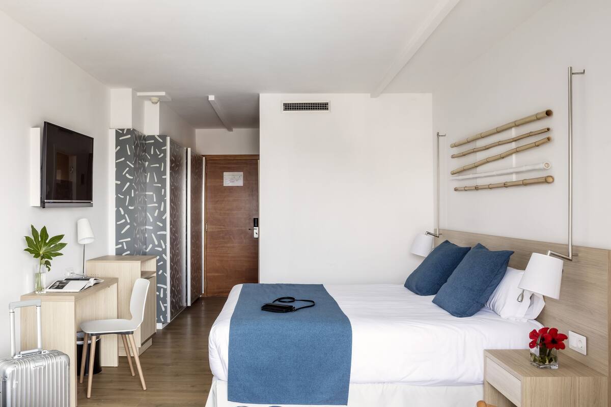 Una habitación de hotel moderna con cama, mesita de noche, lámpara e iluminación de pared.