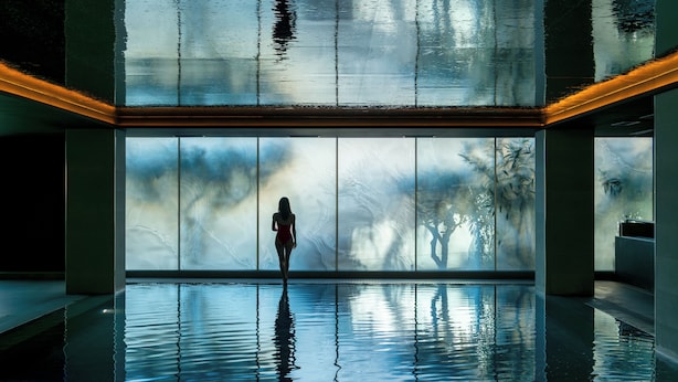 Una amplia piscina interior con vistas despejadas al cielo a través de grandes ventanales.
