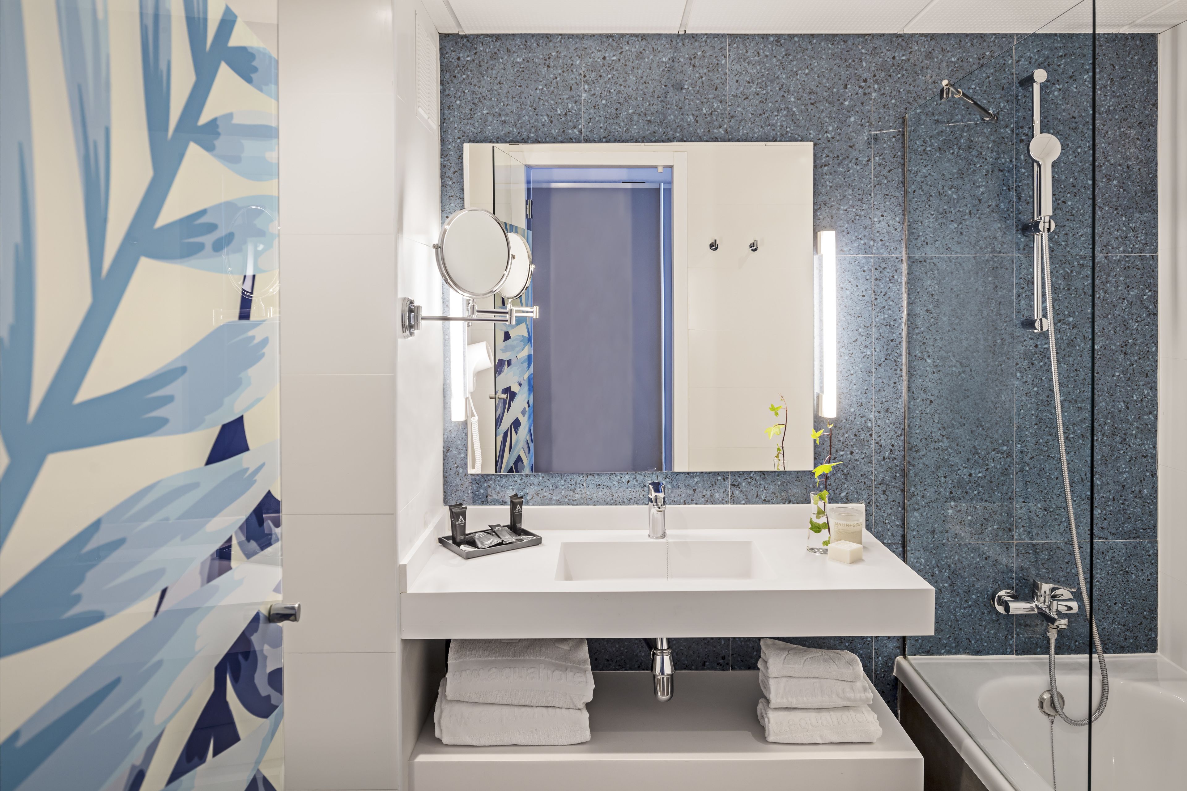 A modern bathroom with a white sink, mirror, and shower.