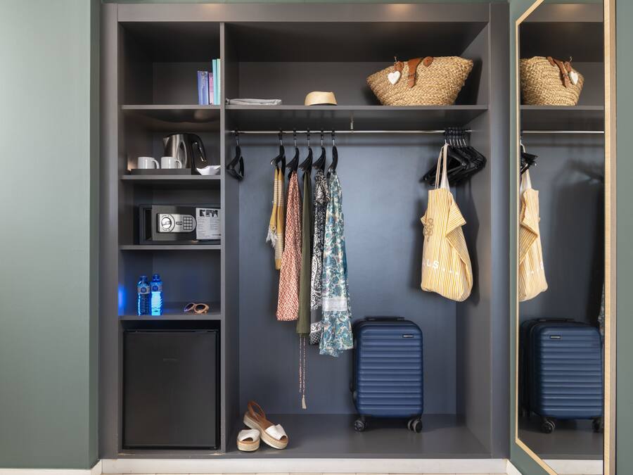 A walk-in closet with shelves, a hanging rack, and a suitcase.