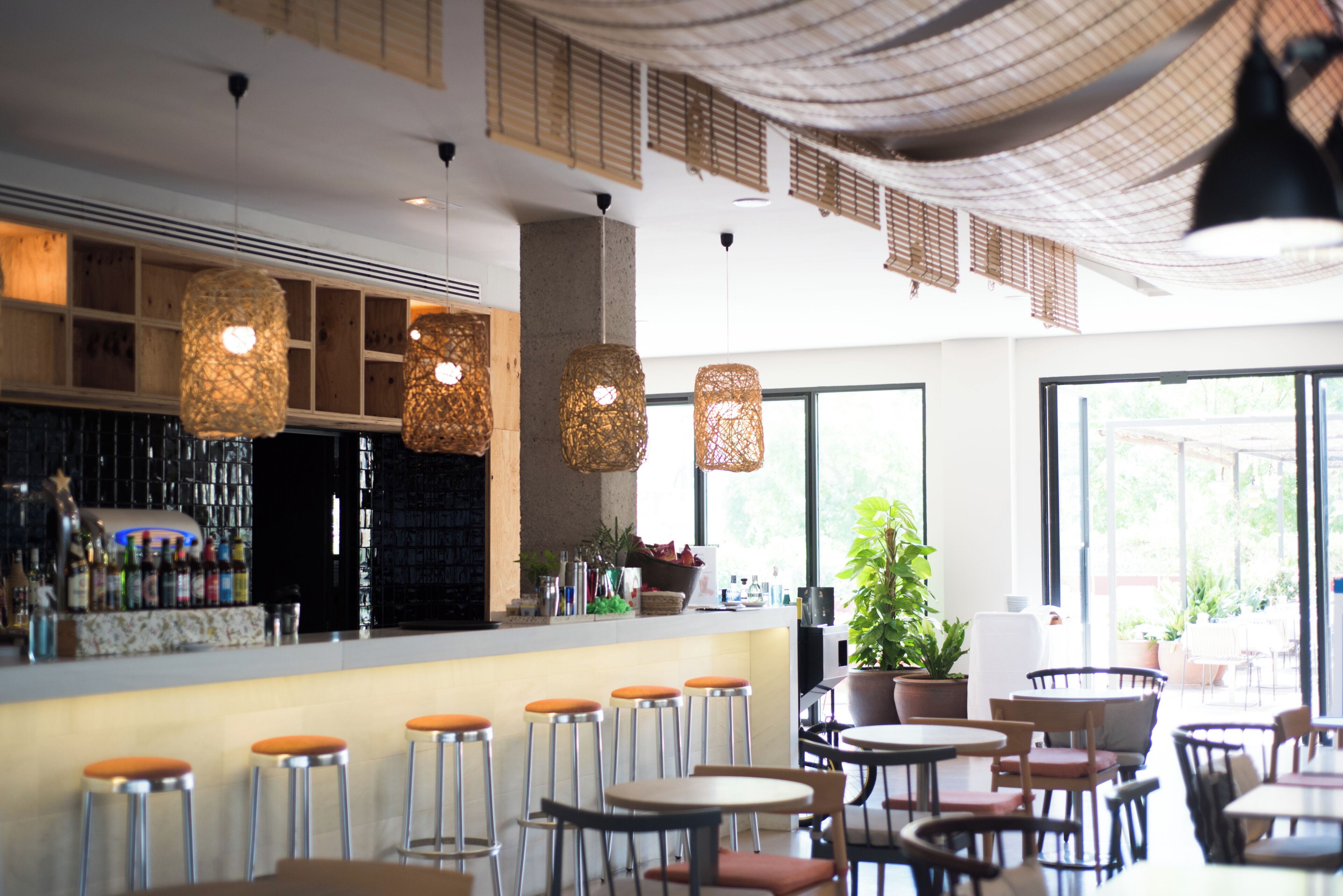 A bar area with stools, hanging lights, and a counter with bottles.