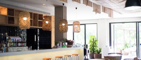 A bar area with stools, hanging lights, and a counter with bottles.