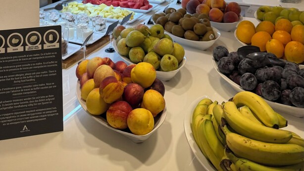 A buffet area with various fruits and a sign indicating dietary options. - AQUA Hotel Bertran Park (Lloret de Mar)