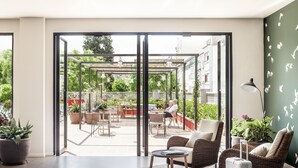 A modern living room with a large sliding glass door leading to an outdoor patio area. - AQUA Hotel Bertran Park (Lloret de Mar)