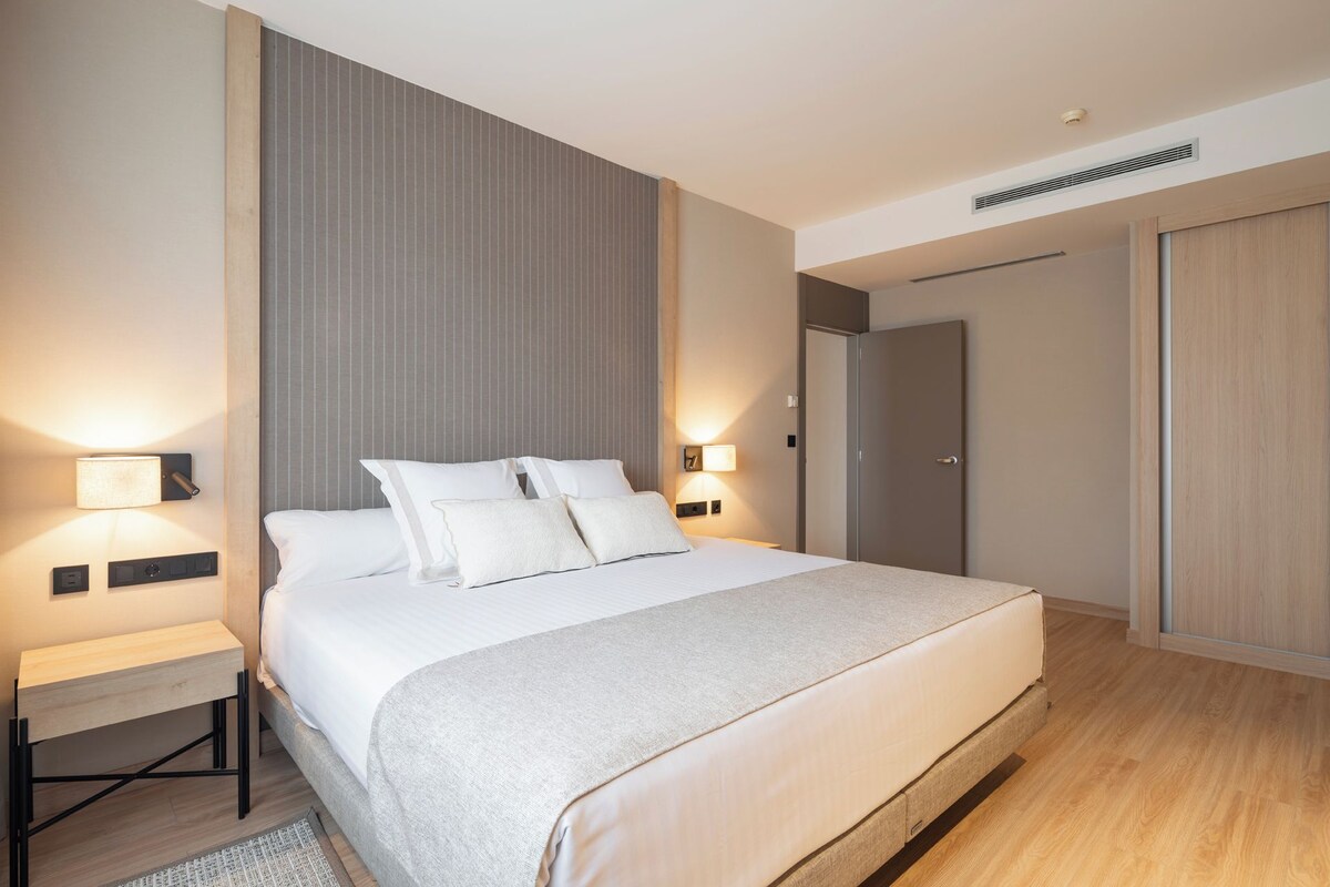 Une chambre d’hôtel moderne, dotée d’un grand lit, de tables de chevet et d’une armoire.