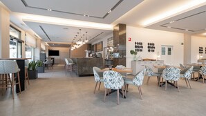 Un moderno vestíbulo de hotel con zona de bar, asientos y una amplia pantalla de televisión.