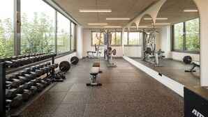 Un gimnasio con equipo de levantamiento de pesas, cintas de correr y máquinas de cardio.