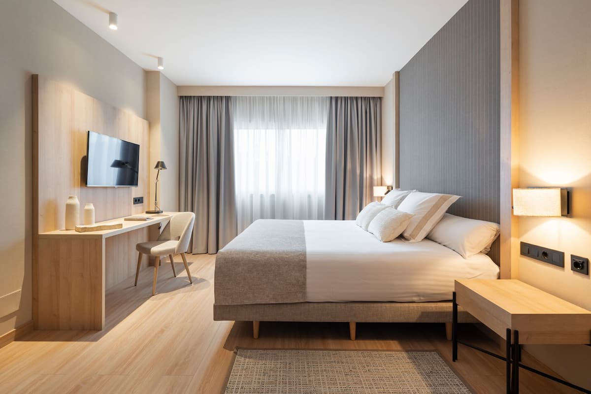 Una habitación de hotel moderna con cama, escritorio, silla y televisión.