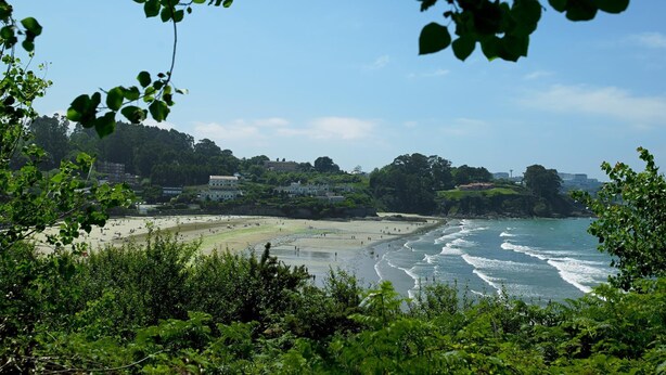 Una playa con vista al océano y un pueblo al fondo.