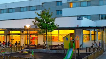 Welcome to our hotel, featuring a modern design with a spacious entrance and a children's play area with a slide and benches.
