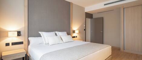 Una habitación de hotel moderna con una cama grande, mesitas de noche y un armario.