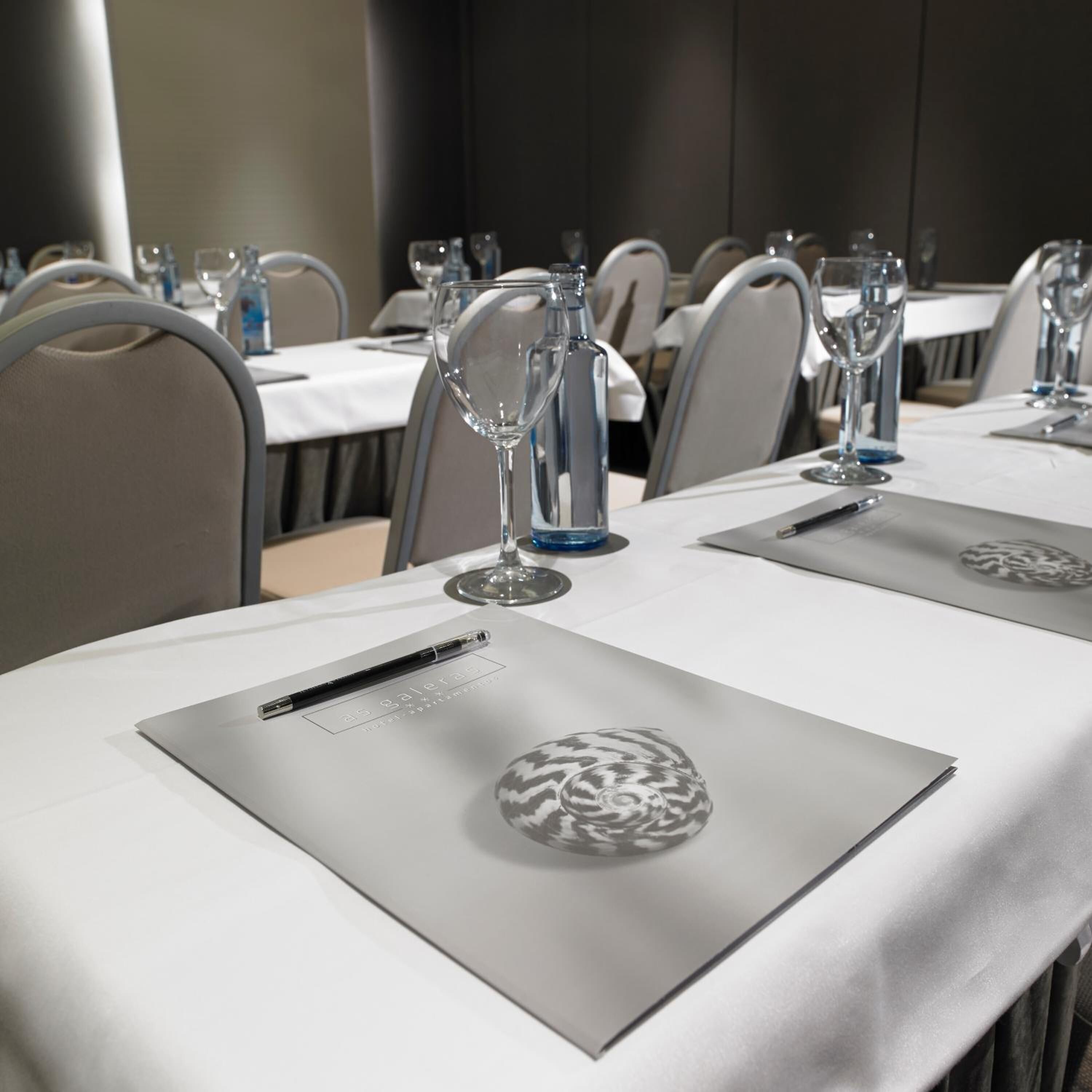A hotel dining area with tables set for guests, each with a menu, a pen, and a glass.