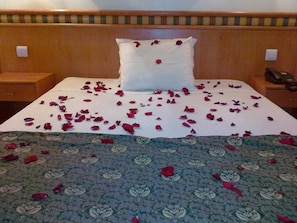 A hotel room with a bed, a pillow, a bedside table, and a patterned bedspread. - Real Caparica Hotel (Almada)