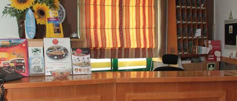 A reception desk with a clock, a vase of sunflowers, and a welcome sign in multiple languages.