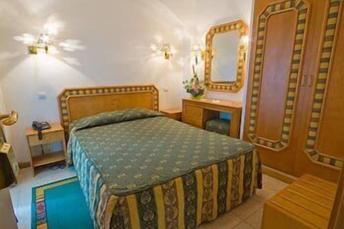 Ein Schlafzimmer mit einem Bett, einem Schminktisch, einem Spiegel und einem Nachttisch.