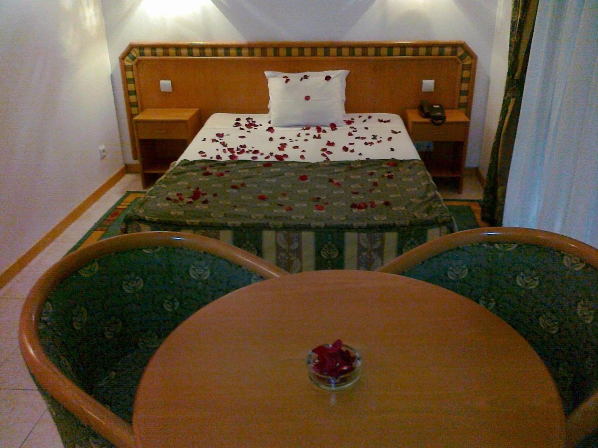 Une chambre d’hôtel avec un lit, deux chaises, une petite table et une table de chevet avec un téléphone.