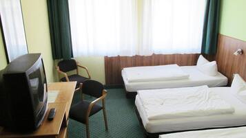 A hotel room with two single beds, a desk with a television and remote control, a chair, and a window with curtains.