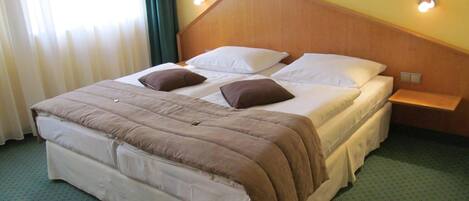 Una habitación de hotel con una cama, una mesita de noche y una lámpara fijada a la pared.