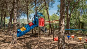 Explore a playground amidst the trees, featuring a slide, climbing structure, and play equipment.