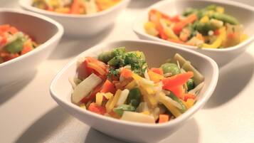 Quatre bols blancs contenant des salades de légumes variées.