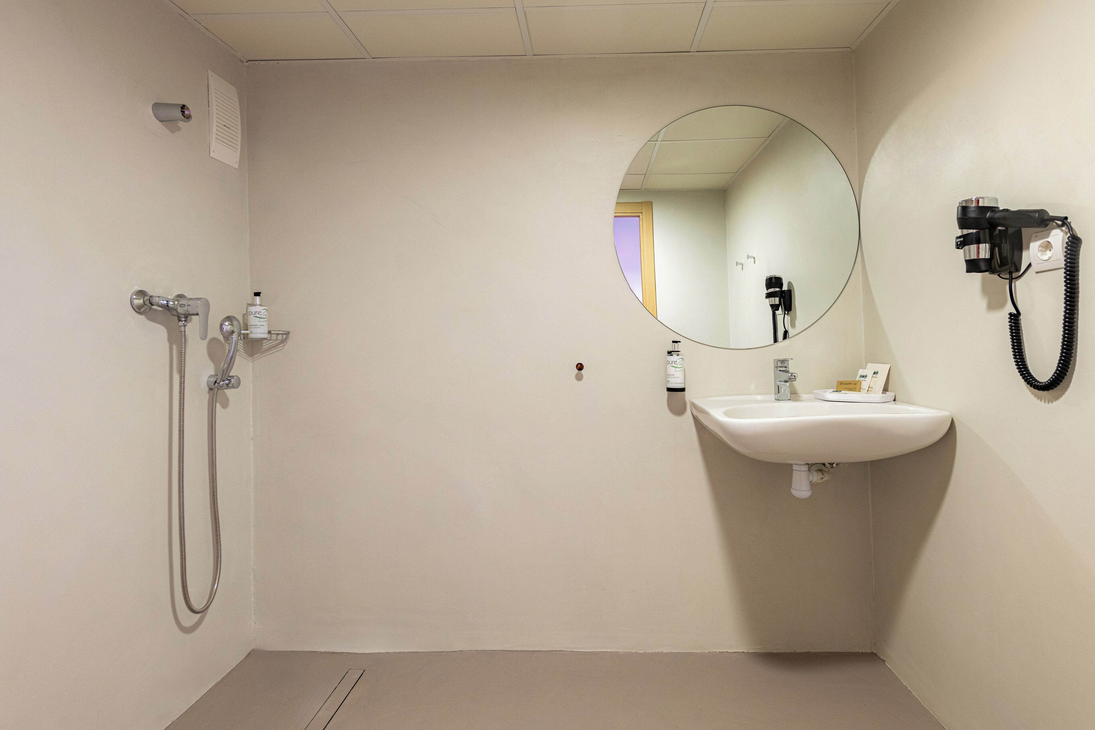 A small, clean bathroom with a sink, mirror, and shower.