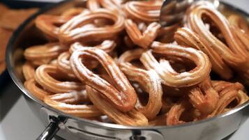 Primer plano de churros en una bandeja de metal, probablemente preparándose o sirviéndose.