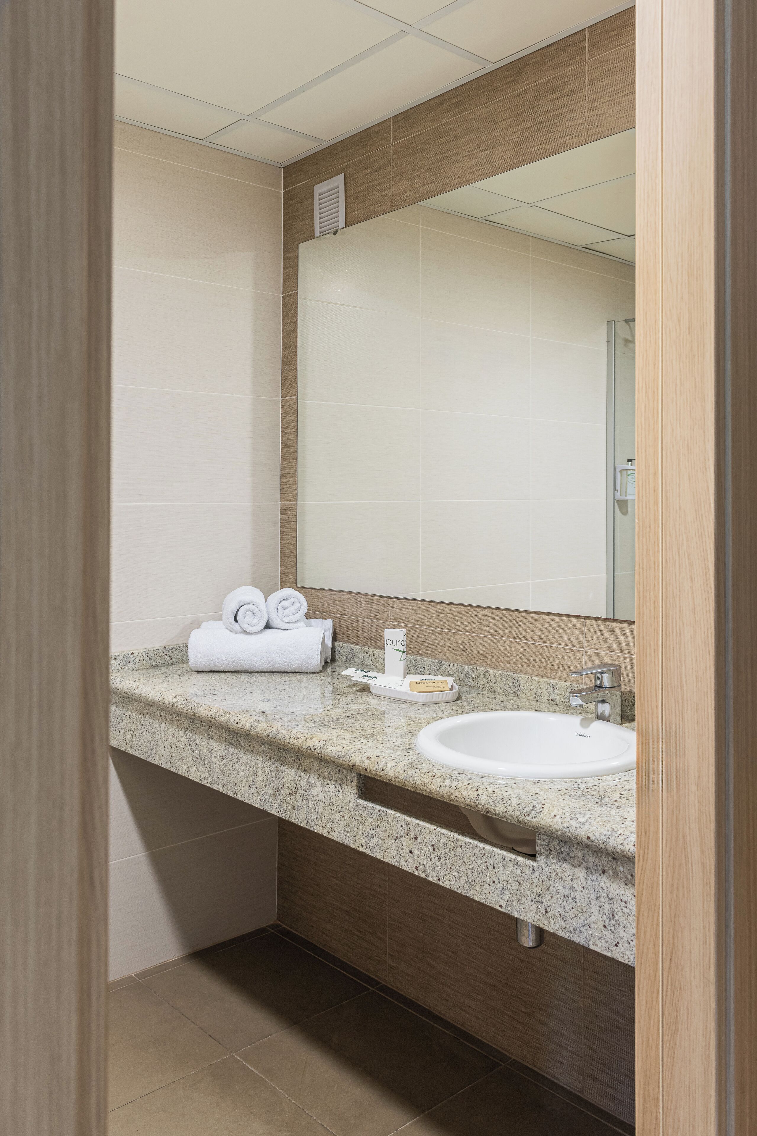 A modern bathroom with a granite countertop, a white sink, and a mirror.