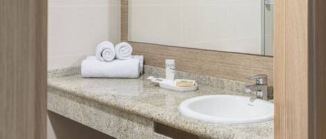 A modern bathroom with a granite countertop, a white sink, and a mirror.