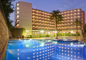 Un hotel con piscina, varios pisos y una fachada bien iluminada.