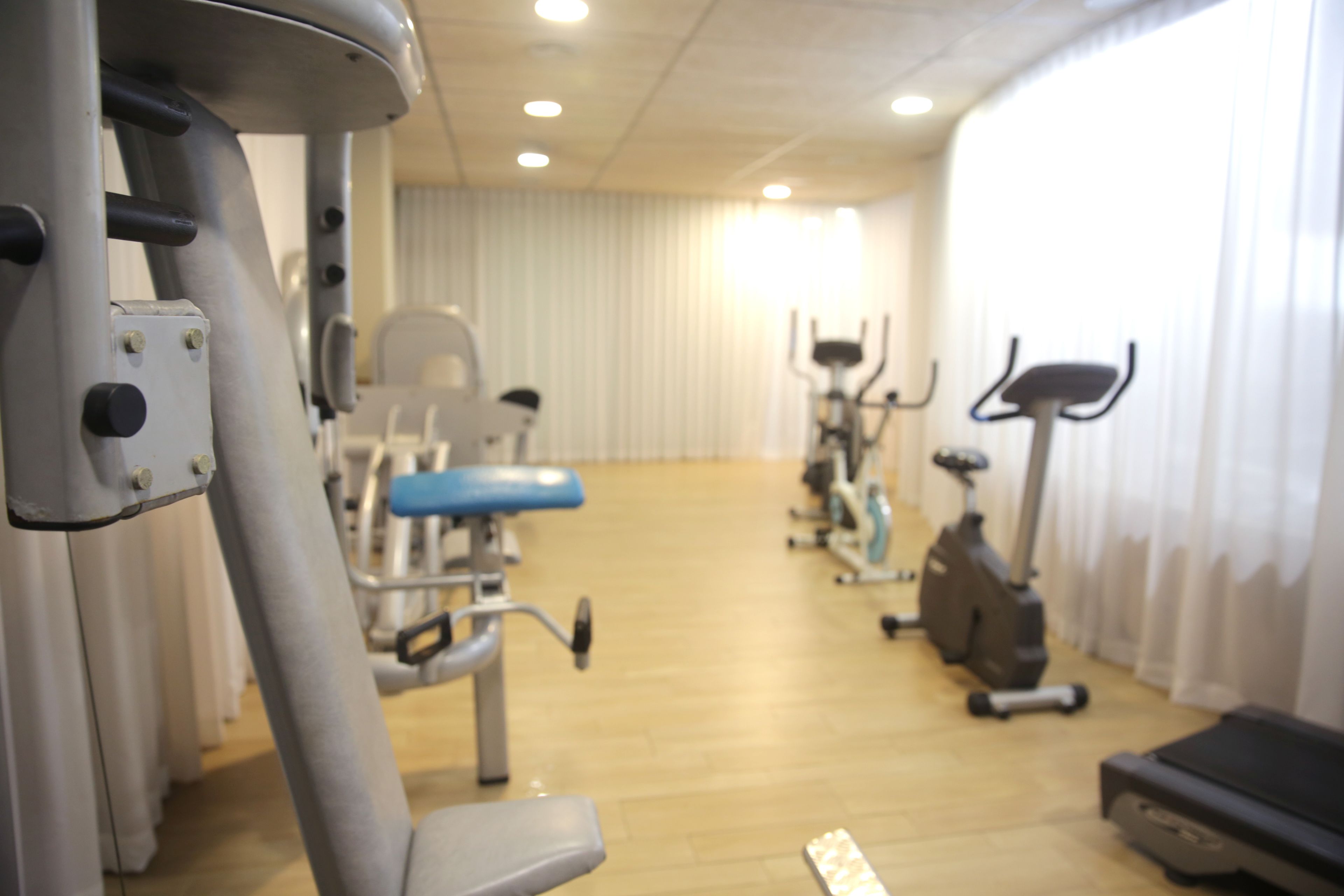A gym with exercise equipment, a treadmill, and a rowing machine.