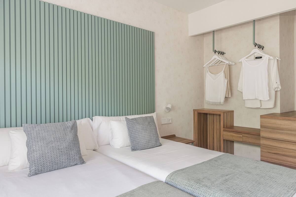 Ein ordentlich eingerichtetes Hotelzimmer mit Bett, Nachttischen und einem Spiegel.