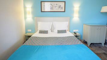 A hotel room with a bed, two bedside tables, a nightstand, a desk, and a chair.