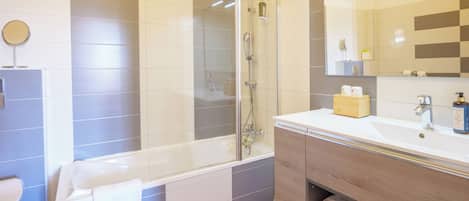 A modern bathroom with a glass-enclosed shower, a white sink with a wooden vanity, and a large mirror.