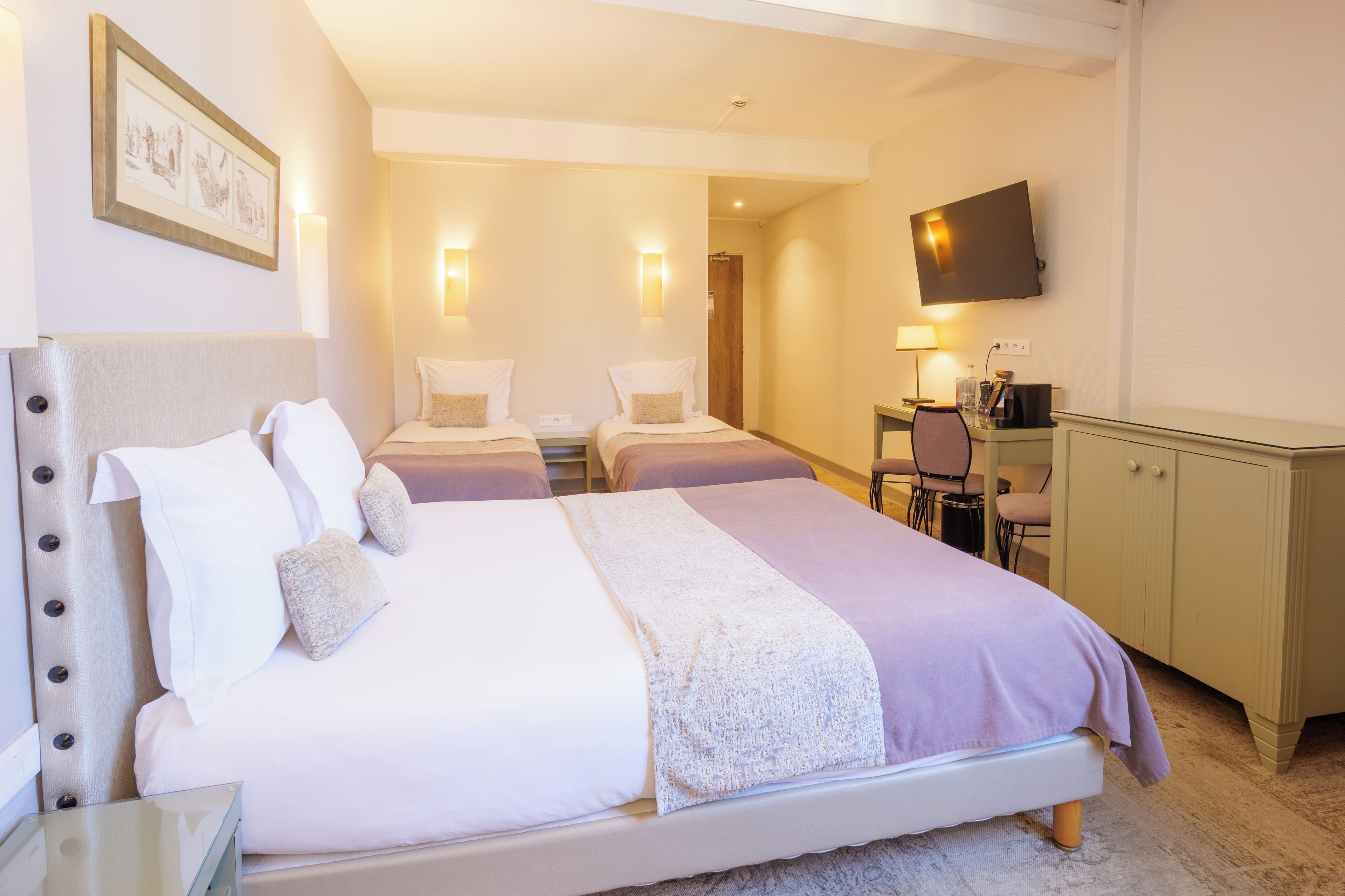 A hotel room with a large bed, a desk, a chair, a television, and a cabinet.