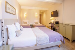 Una habitación de hotel con una cama grande, un escritorio, una silla, un televisor y un armario.