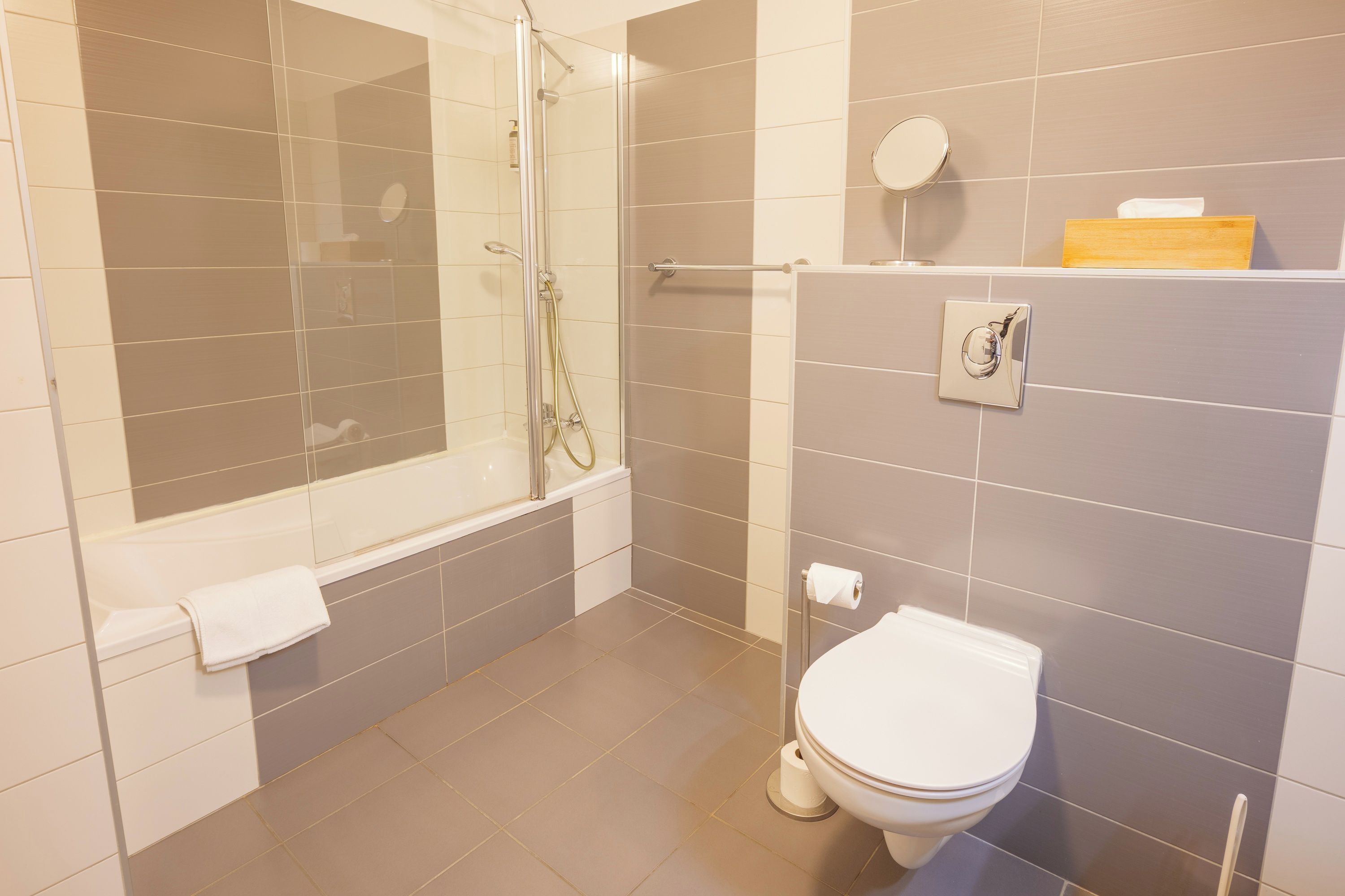 Een badkamer met een douche met glazen wand, een toilet en een handdoekhouder.