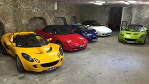 Un estacionamiento con cinco coches deportivos aparcados en fila.