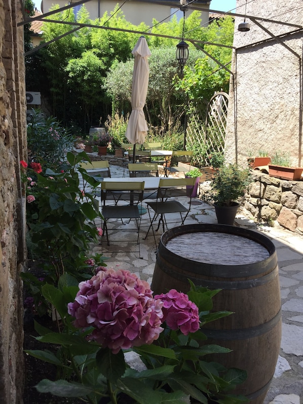 A patio with outdoor furniture, a wooden barrel, and potted plants. - Hotel du Pont Vieux, au pied de la Cité Médiévale (Carcassonne)