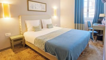 Ein Hotelzimmer mit Bett, Nachttischen, einem Schreibtisch und einem Sessel.