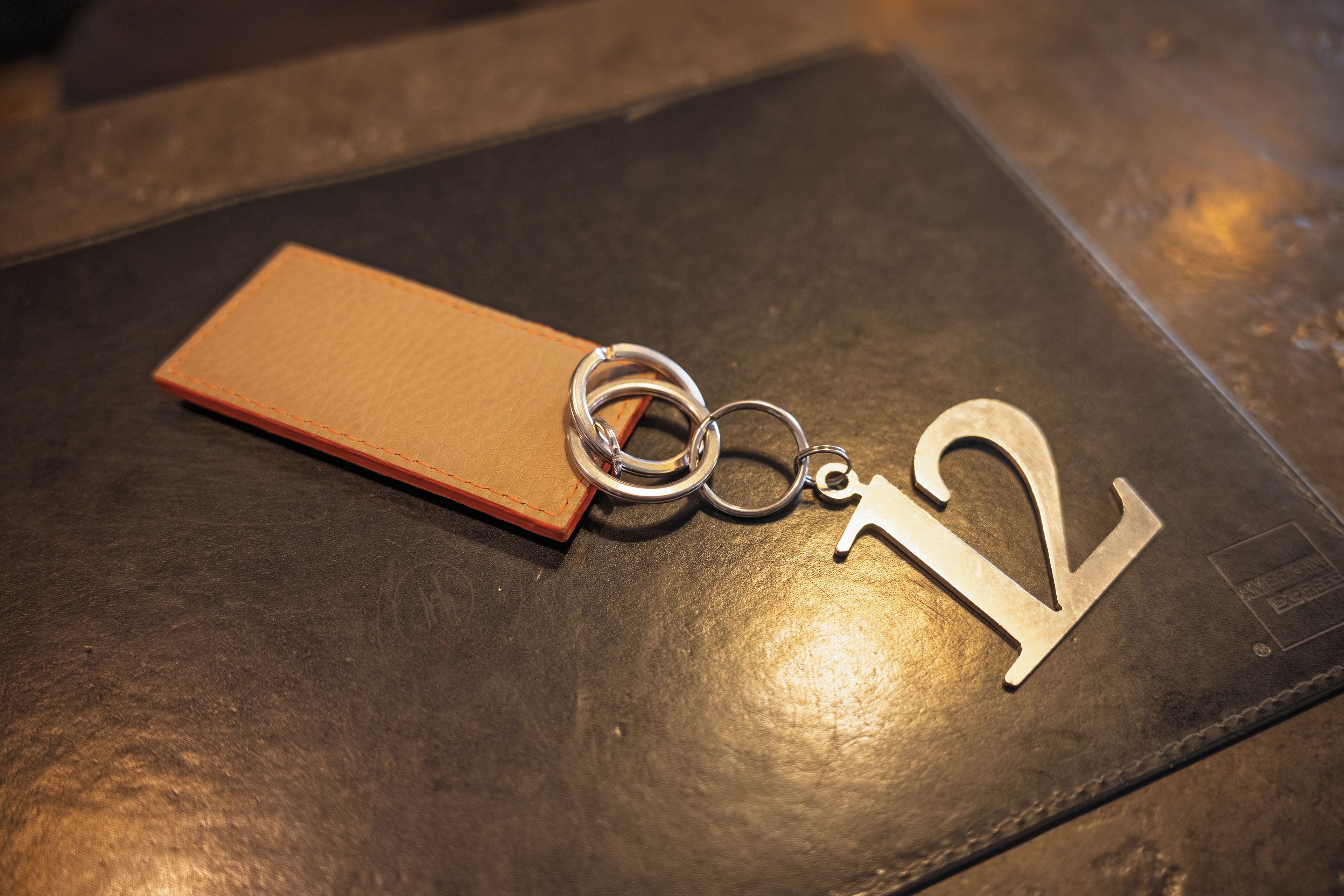 A keychain with a metal number 2 and a brown leather tag on a dark surface.