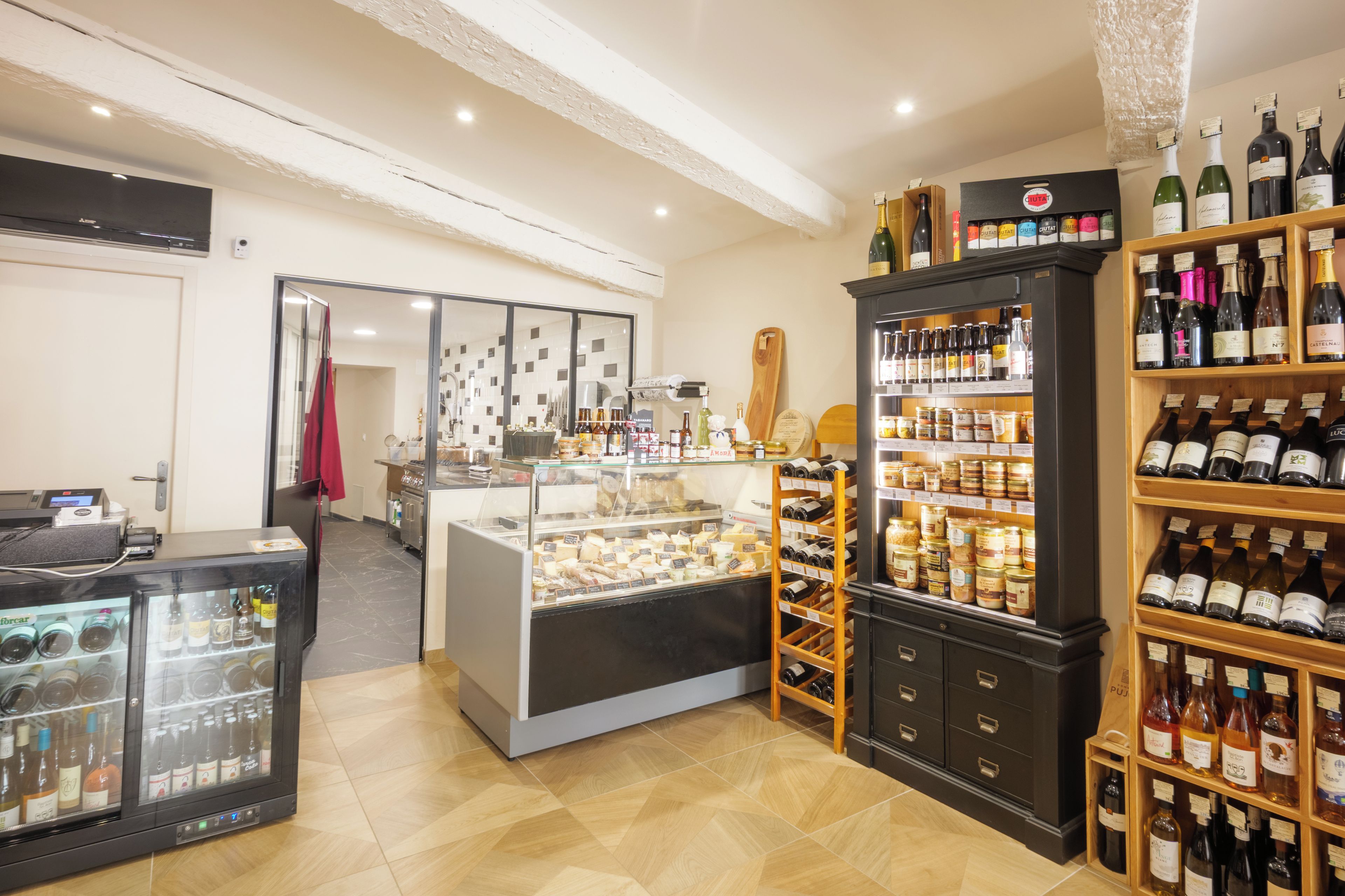 Une cave à vin avec des étagères remplies de bouteilles et un présentoir de fromages.