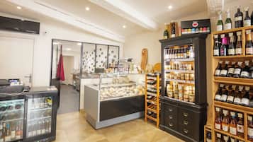 Une cave à vin avec des étagères remplies de bouteilles et un présentoir de fromages.