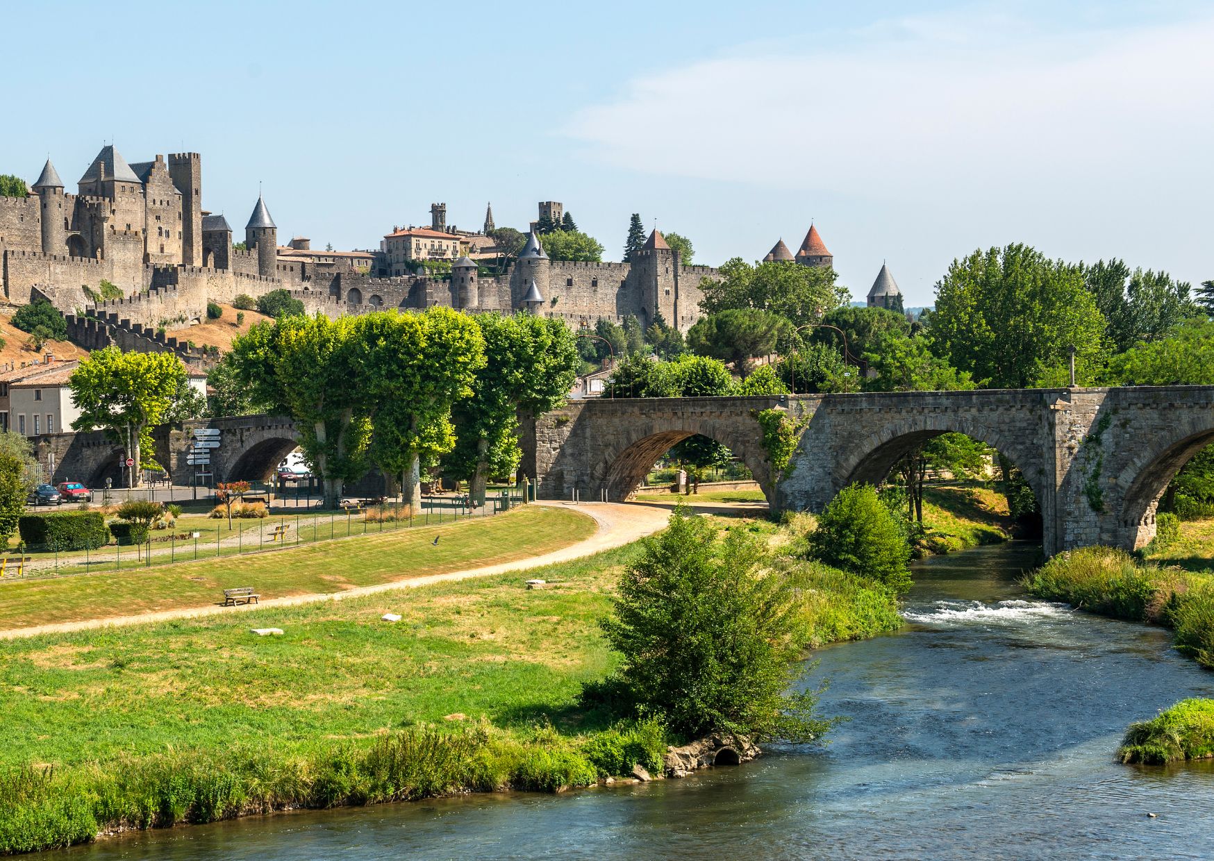 A historic stone bridge over a river, leading to a fortified castle with multiple towers.